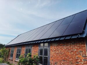 Toiture en tuiles noires avec panneaux solaires intégrés sur maison en briques en Bretagne