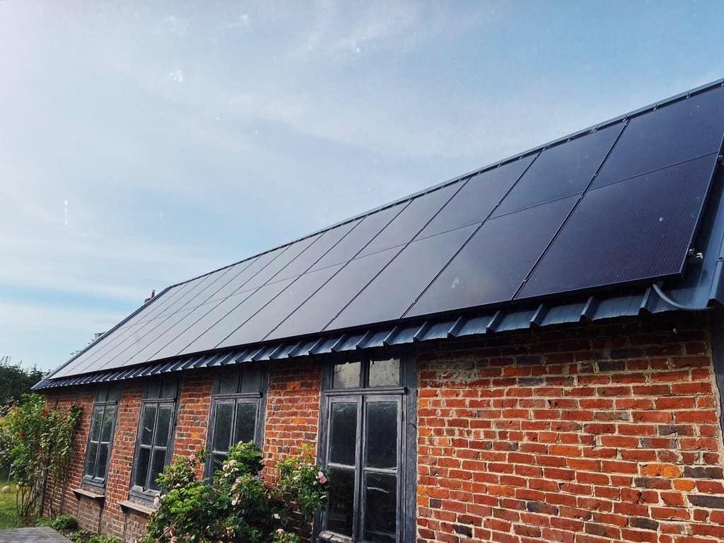 Toiture en tuiles noires avec panneaux solaires intégrés sur maison en briques en Bretagne